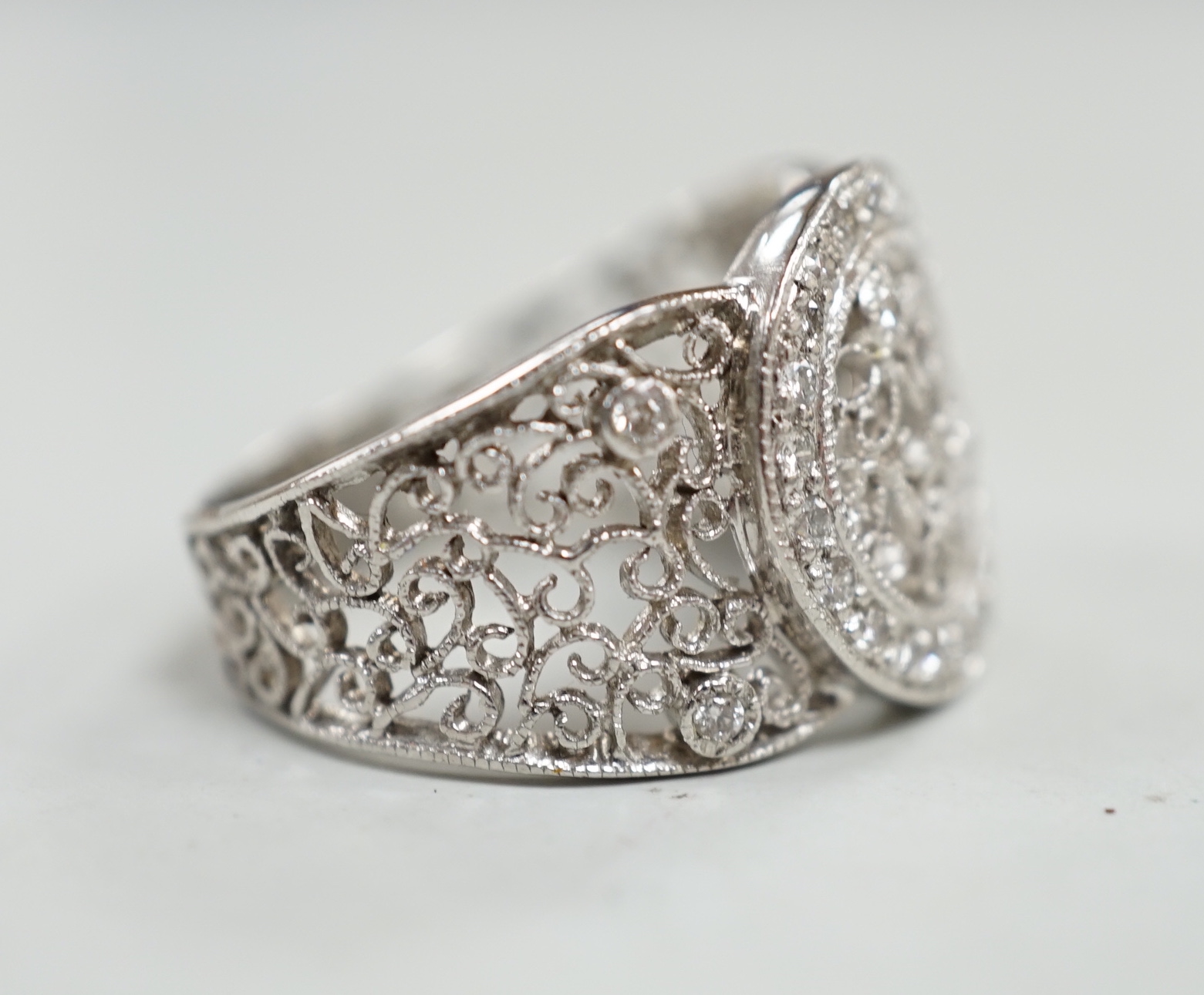 A pierced white metal and diamond chip set diamond ring, with scrolling decoration, size Q/R, gross weight 10.4 grams.